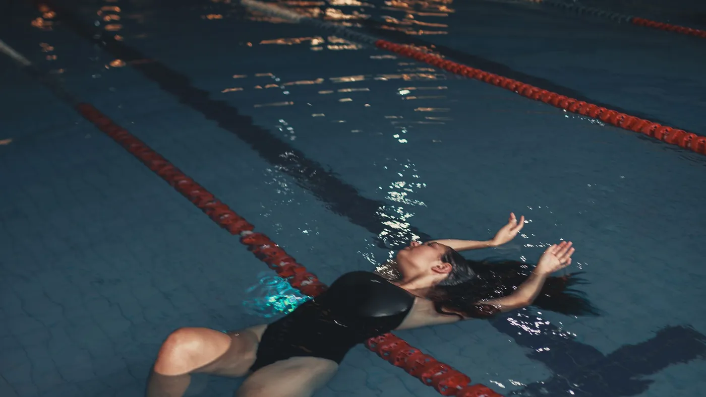 Schwimmerin von oben in ihrer Bahn zwischen zwei Bahnentrennleinen