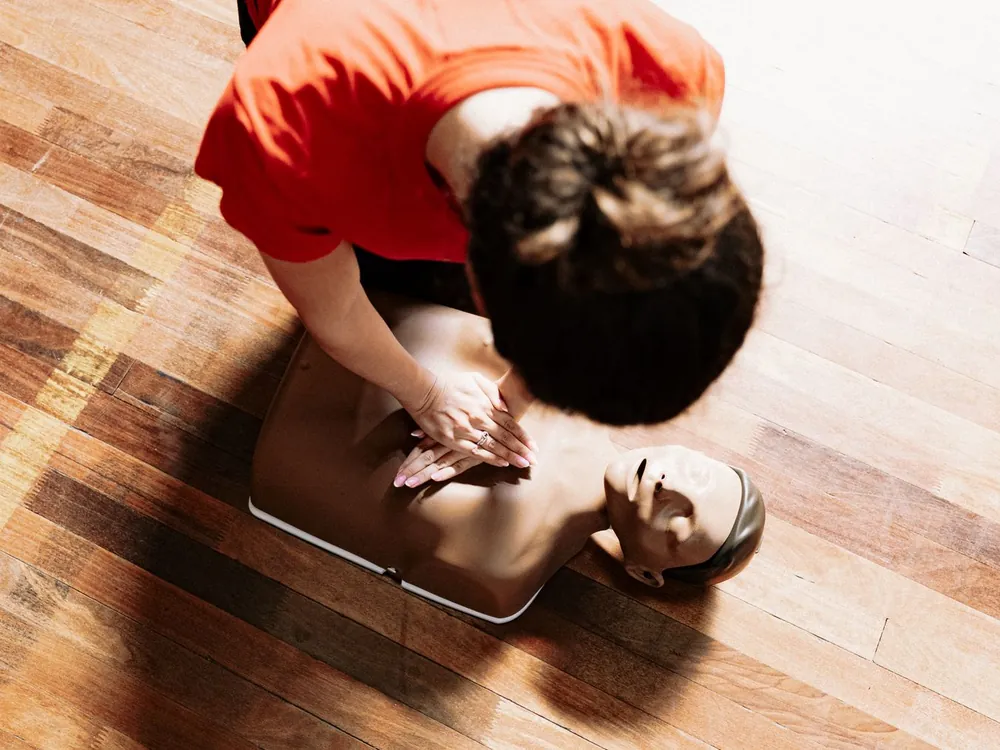 Person übt Herzdruckmassage an einer Reanimationspuppe