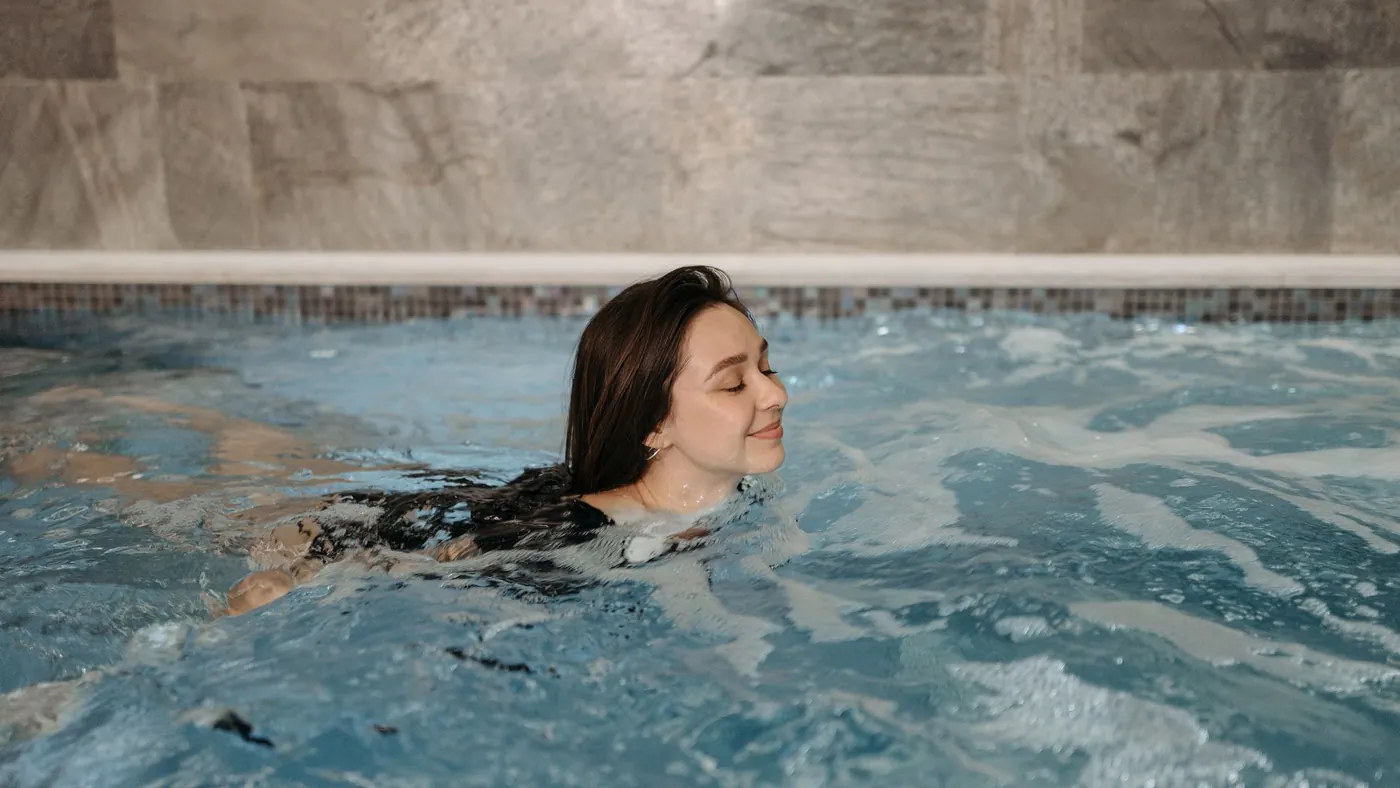 Schwimmerin taucht lächelnd aus dem Wasser auf