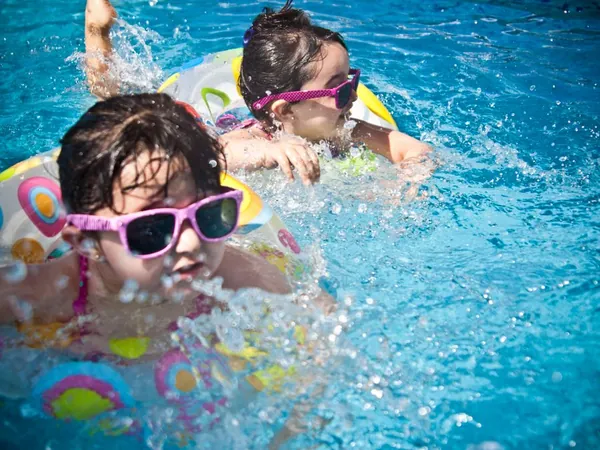 Zwei Kinder mit Schwimmhilfen im Wasser während eines Schwimmkurses