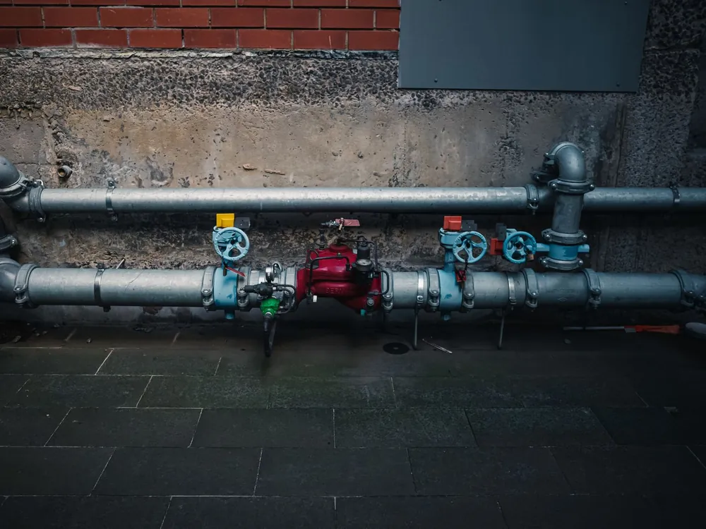 Industrielle Wasserleitungen mit farbigen Absperrventilen an einer Wand